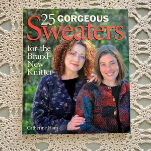 May include: A book cover with the title "25 GORGEOUS Sweaters" and the subtitle "for the Brand-New Knitter" features two women wearing colorful sweaters. The author's name, Catherine Ham, is at the bottom. The background is a light-colored, open-weave textile.