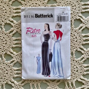 Puede incluir: Un patrón de costura Butterick vintage, B5136, con un diseño Retro '48. El sobre muestra ilustraciones de elegantes vestidos de noche. La paleta de colores incluye negro, rojo y azul, con el rango de tallas indicado en la esquina superior derecha.