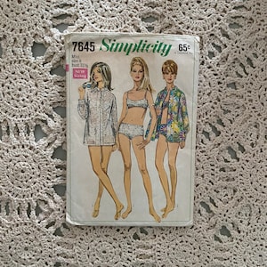 May include: Vintage Simplicity sewing pattern number 7645 for a miss size 8 with a 31 1/2 inch bust. The pattern includes three different looks: a long-sleeved shirt with a floral print, a bikini top and bottom, and a short-sleeved shirt with a floral print. The pattern is labeled "New Sizing" and costs 65 cents.