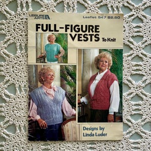 May include: A vintage knitting pattern booklet titled "FULL-FIGURE VESTS To Knit" by Linda Luder. The cover features images of women wearing knitted vests in various colors. The booklet is set against a cream-colored, open-weave background.