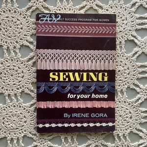 May include: A vintage book titled "SEWING for your home" by Irene Gora. The cover features various decorative trims in shades of pink, blue, and burgundy. The book is part of the Vanderbilt Success Program for Women.