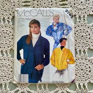 Puede incluir: Un sobre de patrón de costura McCall's vintage con ilustraciones de chaquetas. El sobre tiene un fondo blanco con el texto "McCall's" en la parte superior. El número de patrón es 2763. Las chaquetas son azules y amarillas.