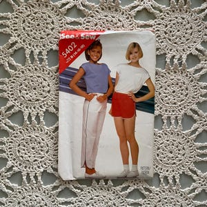 Puede incluir: Un sobre de patrón de costura vintage con dos modelos que llevan ropa informal. El número del patrón es 5402, talla B (14-16-18). El patrón es para una blusa y pantalones.