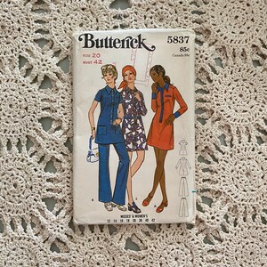 Op de afbeelding: Vintage naaipatroon voor een jurk en broek. Het patroon is voor maten 12-42 en is van Butterick patroonnummer 5837. Het patroon bevat een jurk met een kraag en een knoopsluiting aan de voorkant, en een broek met een wijde pijp.