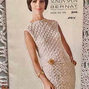 May include: Vintage magazine cover featuring a woman in a cream-colored crochet dress with a matching belt and gold buckle. The cover reads "SUNLIN SPUN" and "BERNAT" with text in the upper right corner. The woman is wearing a gold bracelet.