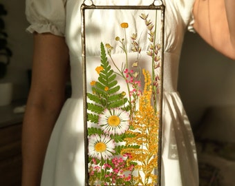 Könnte beinhalten: Ein gerahmtes gepresstes Blumenkunstwerk mit einer Auswahl an gelben, weißen und rosa Blumen und Farnen. Der Rahmen ist aus Metall und hat eine rustikale Optik.