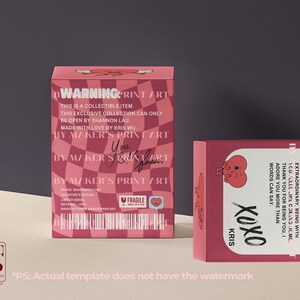 Pode incluir: Caixa colecion&aacute;vel rosa com design de cora&ccedil;&atilde;o e o texto "WARNING PRINT ART". A caixa tem um padr&atilde;o xadrez e inclui texto como "Made with love by Kris Wu" e "By Maker's Print Art". Uma segunda caixa &eacute; vis&iacute;vel com "XOXO Kris".