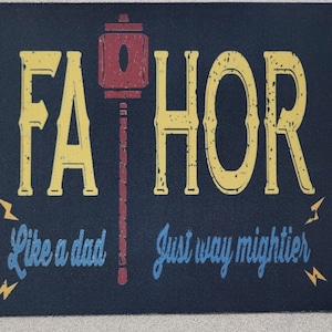May include: A black mousepad with the text "FAHOR" in yellow letters with a distressed look. The text "Like a dad, just way mightier" is in blue letters with a distressed look. A red and gold hammer is in the center of the mousepad.