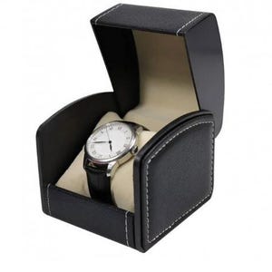 May include: A black leatherette watch box with white contrast stitching, featuring an open lid and a cream-colored interior cushion. Inside, a silver-toned wristwatch with a white face and a black leather strap is displayed on the cushion.