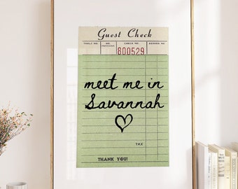 May include: A framed print of a vintage guest check with the text "meet me in Savannah" written in black cursive with a heart drawn below the text. The check number is 1800529.