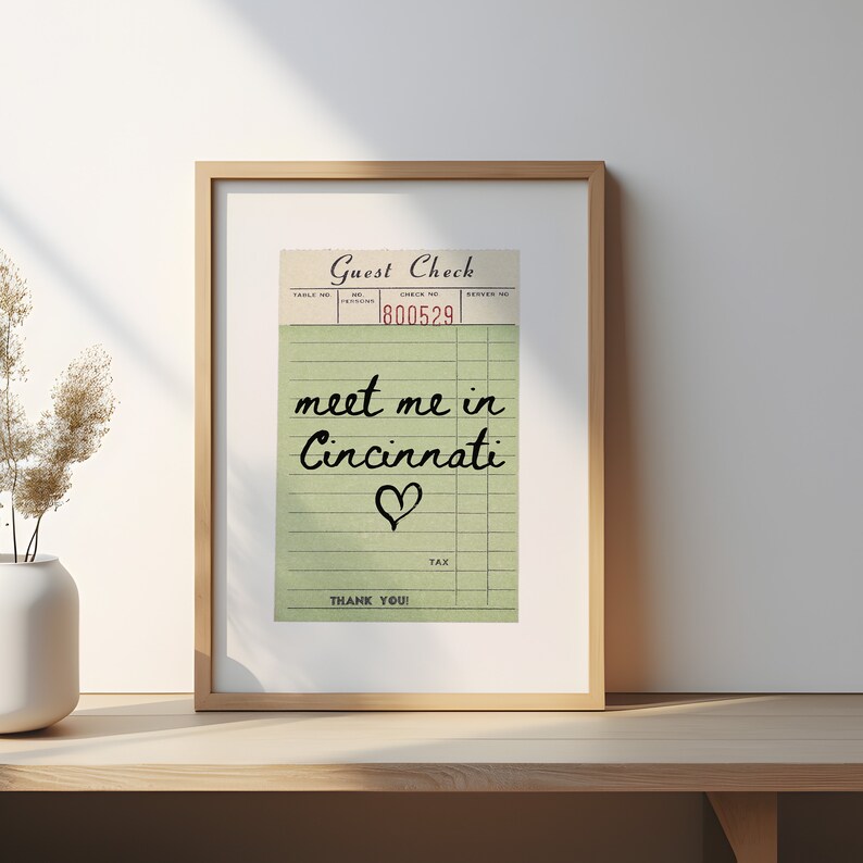 May include: A vintage-style guest check with the text "meet me in Cincinnati" written in black cursive with a red heart underneath. The check number is 800529.