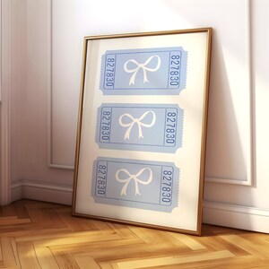 May include: A framed print with three blue tickets featuring a white bow on each ticket. The tickets have the number 827830 printed on them.