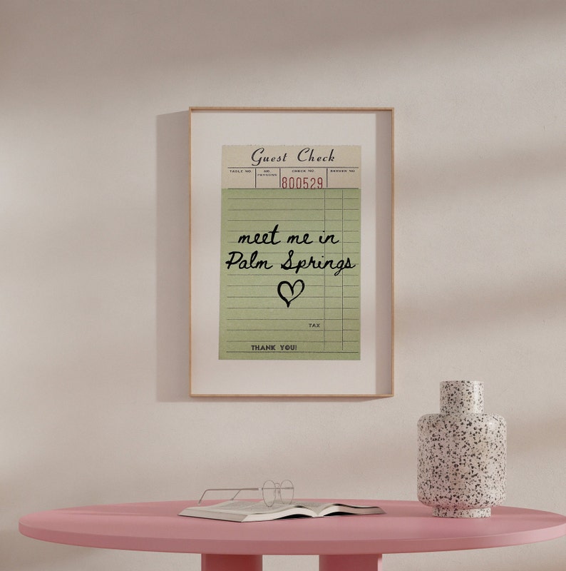 Puede incluir: Una impresi&oacute;n enmarcada de un cheque de hu&eacute;sped vintage con el mensaje escrito a mano "meet me in Palm Springs" y un coraz&oacute;n dibujado debajo. El n&uacute;mero de cheque es 800529.