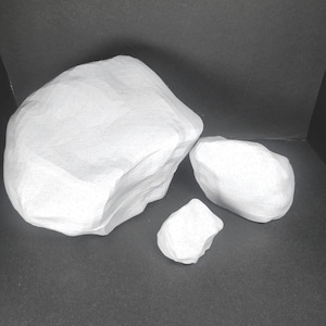 Può includere: Tre pietre bianche di diverse dimensioni. La pietra più grande è liscia e ha una forma arrotondata. La pietra di medie dimensioni è più angolare. La pietra più piccola è una piccola forma irregolare.