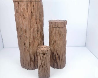 Puede incluir: Tres contenedores de madera con forma de tronco de árbol. El contenedor más grande mide aproximadamente 25 cm de alto, el contenedor del medio mide aproximadamente 15 cm de alto y el contenedor más pequeño mide aproximadamente 10 cm de alto.