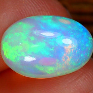 May include: A polished, oval-shaped opal gemstone. The opal displays a vibrant play-of-color, with flashes of green, blue, and orange hues. The stone has a smooth, glossy surface, reflecting light and creating a captivating visual effect.