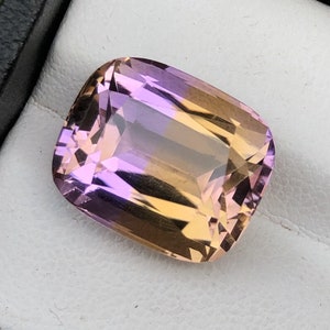 May include: A large, faceted, rectangular gemstone with a gradient of purple to orange.