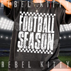 Pu&ograve; includere: Una t-shirt a maniche corte color nero antracite con una stampa grafica bianca dall'effetto consumato che riporta la scritta FOOTBALL SEASON in grassetto maiuscolo, incorniciata da un motivo a scacchi sopra e sotto il blocco di testo.