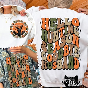 May include: White sweatshirt with the text "HELLO HUNTING SEASON GOODBYE HUSBAND" in orange, green, and brown. A second sweatshirt in camouflage has the same text. A circular graphic with a deer is also visible.