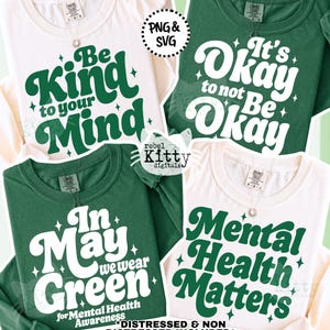May include: Four t-shirts with mental health awareness slogans. Two are cream-colored, and two are green. The phrases include "Be Kind to your Mind," "It's Okay to not Be Okay," "In May we wear Green," and "Mental Health Matters."