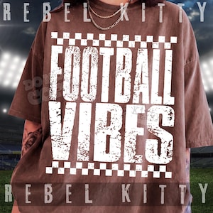 Pu&ograve; includere: Una t-shirt marrone a maniche corte con una stampa grafica bianca con il testo FOOTBALL VIBES in un carattere usurato. Il design &egrave; incorniciato da un bordo a scacchi nella parte superiore e inferiore. La maglietta ha un girocollo e una vestibilit&agrave; ampia.