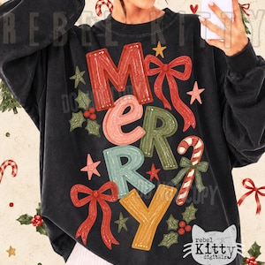 Può includere: Una felpa nera a maniche lunghe con la parola MERRY in grandi lettere testurizzate multicolori. Il design include fiocchi rossi, un bastoncino di zucchero, foglie di agrifoglio verdi e piccole stelle. Il testo REBEL KITTY e un logo di gatto.
