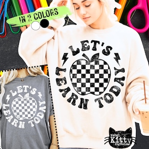 May include: Cream-colored sweatshirt and gray t-shirt featuring a black and white checkered apple graphic with the text "LET'S LEARN TODAY". The image also includes the text "IN 2 COLORS" and the logo "rebel Kitty digitals".