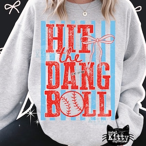 Peut inclure: Un sweat-shirt gris clair avec un motif sur le thème du baseball. Le motif présente les mots "HIT the DANG BALL" en lettres rouges, un graphique de baseball et des rayures verticales bleu clair.