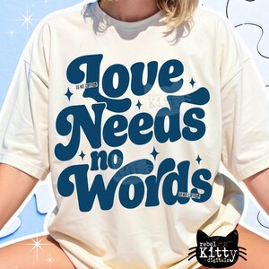 May include: Cream-colored t-shirt with the text "Love Needs no Words" in dark blue, stylized font. The design includes star accents and the words "DO NOT COPY" in small print. A black cat logo is visible at the bottom.