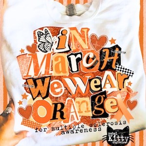 May include: White sweatshirt with the text "In March We Wear Orange" in orange and black block letters, with a butterfly and hearts. The text "for multiple sclerosis awareness" is below the main text.