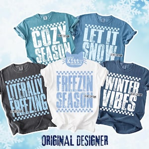 May include: Five t-shirts in various colors, each with a winter-themed phrase in a bold, white font. Phrases include "Cozy Season," "Let It Snow," "Literally Freezing," "Freezin Season," and "Winter Vibes." The shirts have a checkered border.