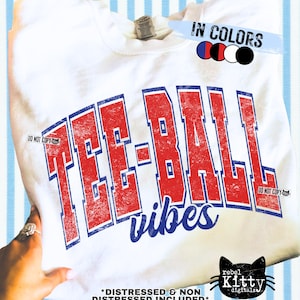 Puede incluir: Sudadera blanca con las palabras "TEE-BALL vibes" en letras rojas y azules desgastadas. La sudadera de cuello redondo tiene las palabras "DO NOT COPY" impresas. Una mano sostiene la sudadera.