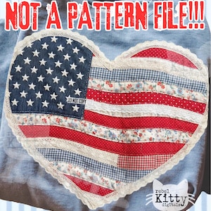 May include: A light blue sweatshirt with a heart-shaped patch featuring the American flag design. The patch includes a blue denim field with white stars, red and white stripes, and floral and gingham patterns. The text "NOT A PATTERN FILE!!!" is at the top.