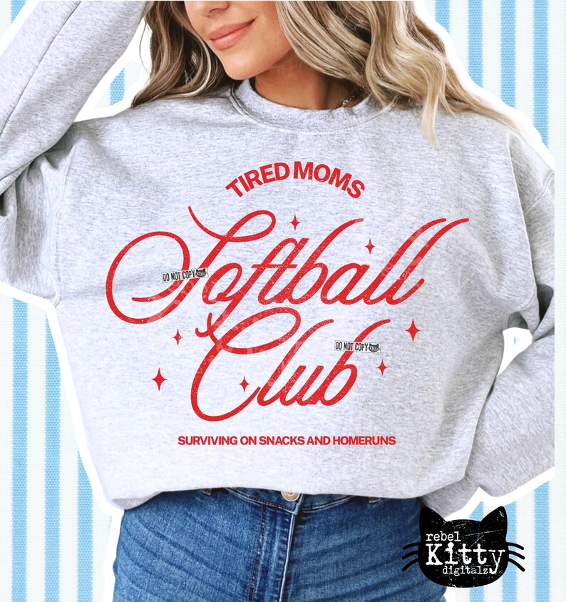 May include: A light gray sweatshirt with the words "TIRED MOMS Softball Club" in red script. The text "SURVIVING ON SNACKS AND HOMERUNS" is below the club name. The sweatshirt has a crew neck and long sleeves.