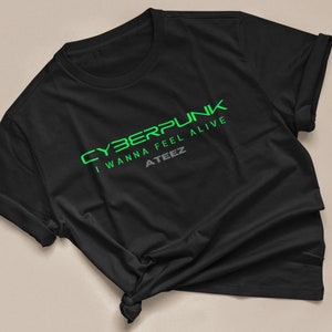 Może przedstawiać: Czarny T-shirt z zielonym nadrukiem, na kt&oacute;rym widnieje napis "CYBERPUNK I WANNA FEEL ALIVE ATEEZ"