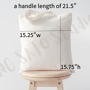 May include: A white canvas tote bag with a handle length of 21.5 inches. The bag measures 15.25 inches wide and 15.75 inches high.
