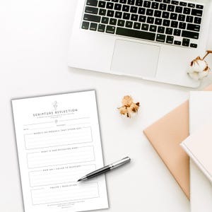 May include: A white paper sheet titled SCRIPTURE REFLECTION with sections for date, passage, words that stood out, what is God revealing here, how am I called to respond, and prayer or resolution, accompanied by a silver and black ballpoint pen.