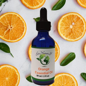 Puede incluir: Una botella de vidrio azul cobalto de Aceite Esencial de Naranja con un cuentagotas negro, etiquetada como "Go Nature Y". La etiqueta también dice "Orange Essential Oil" y "59 ml / 2 fl oz". La botella está rodeada de rodajas de naranja y hojas verdes.