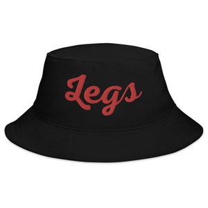 Puede incluir: Sombrero de pescador negro con la palabra "Legs" bordada en rojo.