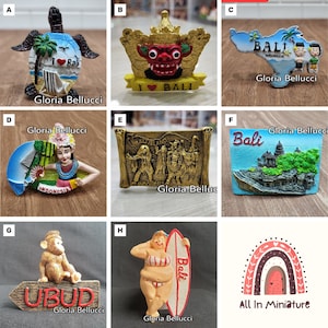 May include: A collection of colourful fridge magnets featuring various designs related to Bali, Indonesia. The magnets include a turtle with a heart and the words "I love Bali", a red demon mask with a crown, a map of Bali with the words "Bali Indonesia", a woman in traditional Balinese clothing, a golden scroll with a scene of Balinese people, a temple with the word "Bali", a monkey sitting on a sign that says "Ubud", a woman on a surfboard with the word "Bali", and a rainbow with the words "All In Miniature".