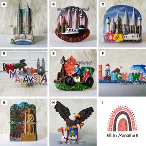 May include: A collection of miniature souvenir magnets featuring Malaysian landmarks and symbols. The magnets showcase the Petronas Towers, historical buildings, and the Langkawi eagle, with the text "Malaysia" and "Langkawi".