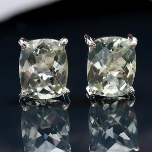 May include: A pair of silver earrings with light green gemstone settings. The gemstones are square-shaped and have a faceted cut.