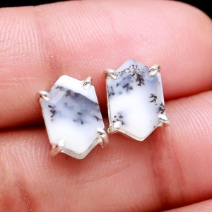 May include: A pair of silver stud earrings with white and black dendritic opal gemstones. The gemstones are hexagonal in shape and have a unique, natural pattern.