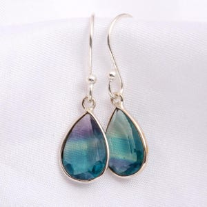 Può includere: Un paio di orecchini a goccia d'argento con pietre preziose di fluorite blu, verde e viola.