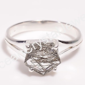 May include: Silver ring with a clear, faceted gemstone with brown inclusions. The gemstone is set in a square-shaped setting with a split shank.