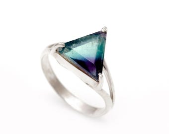 Puede incluir: Un anillo de plata con una piedra preciosa de fluorita triangular verde, azul y púrpura.