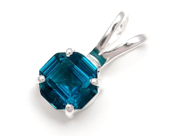 May include: A square-cut, teal-colored gemstone pendant with a silver bail. The gemstone is set in a four-prong setting, and the bail is a simple, curved design. The pendant is displayed against a white background.