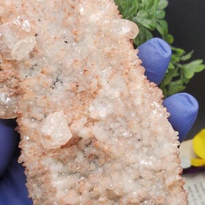 K&ouml;nnte beinhalten: Ein Cluster aus wei&szlig;en und rosafarbenen Kristallen mit einer rauen, strukturierten Oberfl&auml;che. Die Kristalle sind in einem zuf&auml;lligen Muster angeordnet und haben ein nat&uuml;rliches, organisches Aussehen.