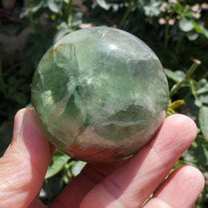 Green and golden flourite crystal sphere with rainbow inclusions 324g