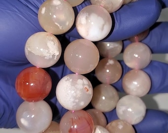 May include: A strand of agate beads in shades of white, pink, and red. The beads are round and have a smooth, polished finish.